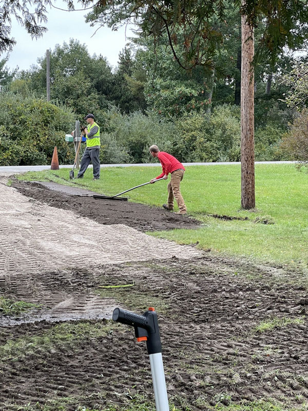 Workers raking gravel on edges of driveway